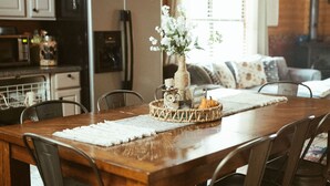 A wooden dining table with chairs, a vase with flowers, and a pumpkin centerpiece. - Mt. Sherman Cabin - Ozark Mountains (Jasper)