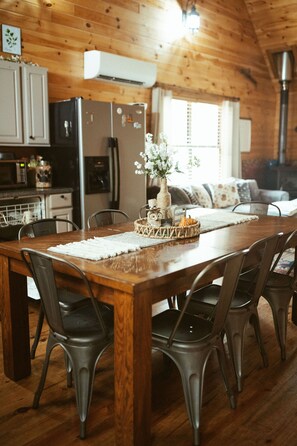 A wooden dining table with chairs, a vase with flowers, and a pumpkin centerpiece.