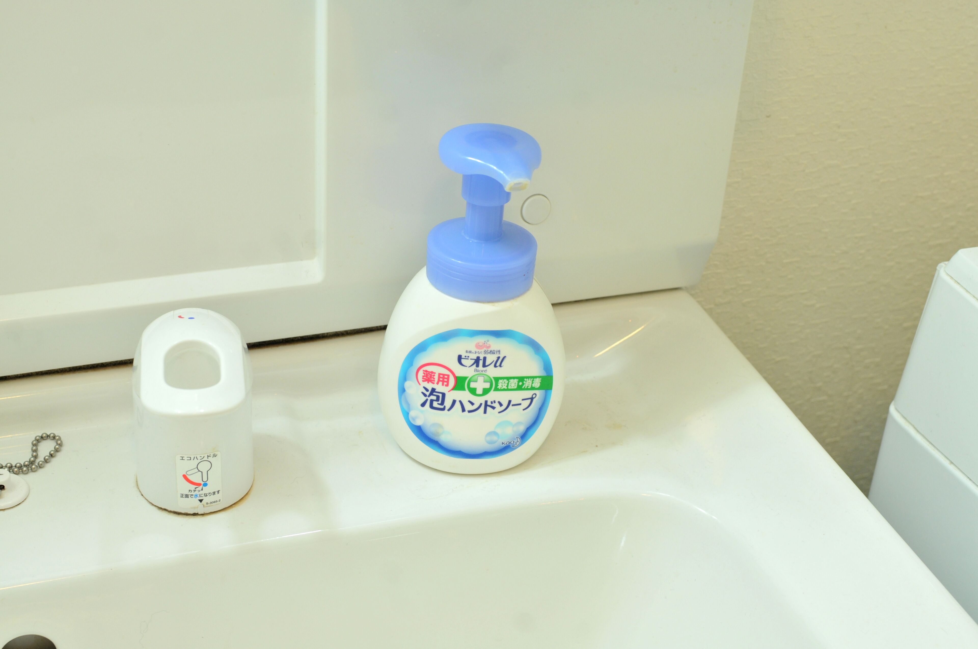 Un lavabo de salle de bain avec un flacon de savon liquide et un distributeur de savon.