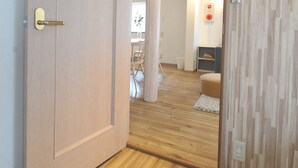 An open door leading to a room with wooden flooring and a patterned wall. - Condominium House Ten-roku (Osaka)