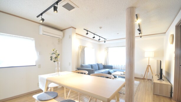 A modern living room with a dining area, a sofa set, and a television. - Condominium House Ten-roku (Osaka)