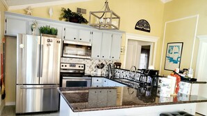 A modern kitchen with a central island, stainless steel appliances, and a decorative welcome sign. - Canal-Front Home, 2-Min Drive to Beach, Fishing Pier. (Galveston)