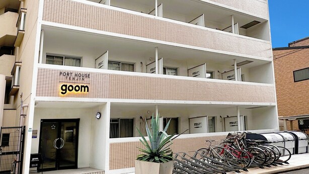 A multi-story building with a tiled facade, a ground-level entrance, and a sign reading "Port House Tanjin goom".