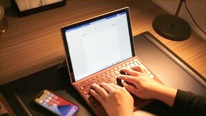 A laptop on a desk with a smartphone nearby.