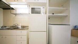 A compact kitchen with white cabinets, a microwave, and a refrigerator.