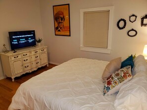 Ein Schlafzimmer mit Bett, Schminktisch, Fernseher, einem Poster und Wanddekorationen.
