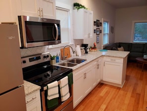 A modern kitchen with white cabinets, stainless steel appliances, and a granite countertop.