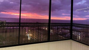 A room with a large window overlooking a cityscape at dusk. - Casa Frida: Luxe Pier 57 Oceanview Corner Unit (Puerto Vallarta)
