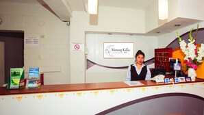 A hotel reception desk with a logo, a receptionist, and a counter with Visa cards and a phone. -  HOTEL MOSOQ KILLA (Cusco)