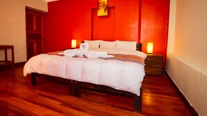 A hotel room with a large bed, wooden flooring, red walls, and two bedside lamps. -  HOTEL MOSOQ KILLA (Cusco)