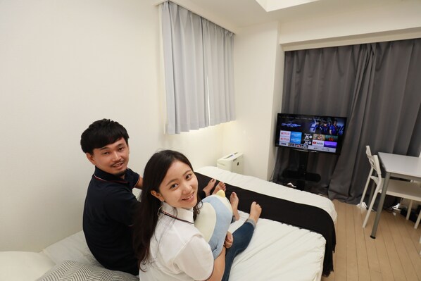 A hotel room with a bed, a television, a desk, and a chair.