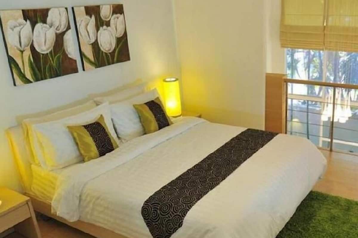 A hotel room with a bed, a nightstand, a lamp, and a window with a view.