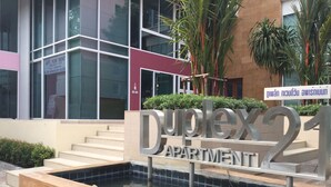Señal para el Apartamento Duplex 21, con diseño moderno, frente a un edificio con grandes ventanales y una escalera.