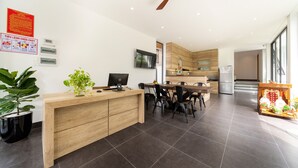 Une cuisine moderne avec un plan de travail en bois, des chaises noires et une table à manger. On aperçoit un réfrigérateur, un four à micro-ondes et un évier au fond.