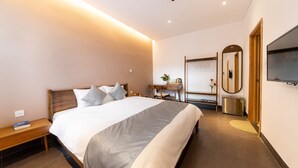 Une chambre d’hôtel moderne avec un grand lit, une table de chevet et un bureau avec une chaise.