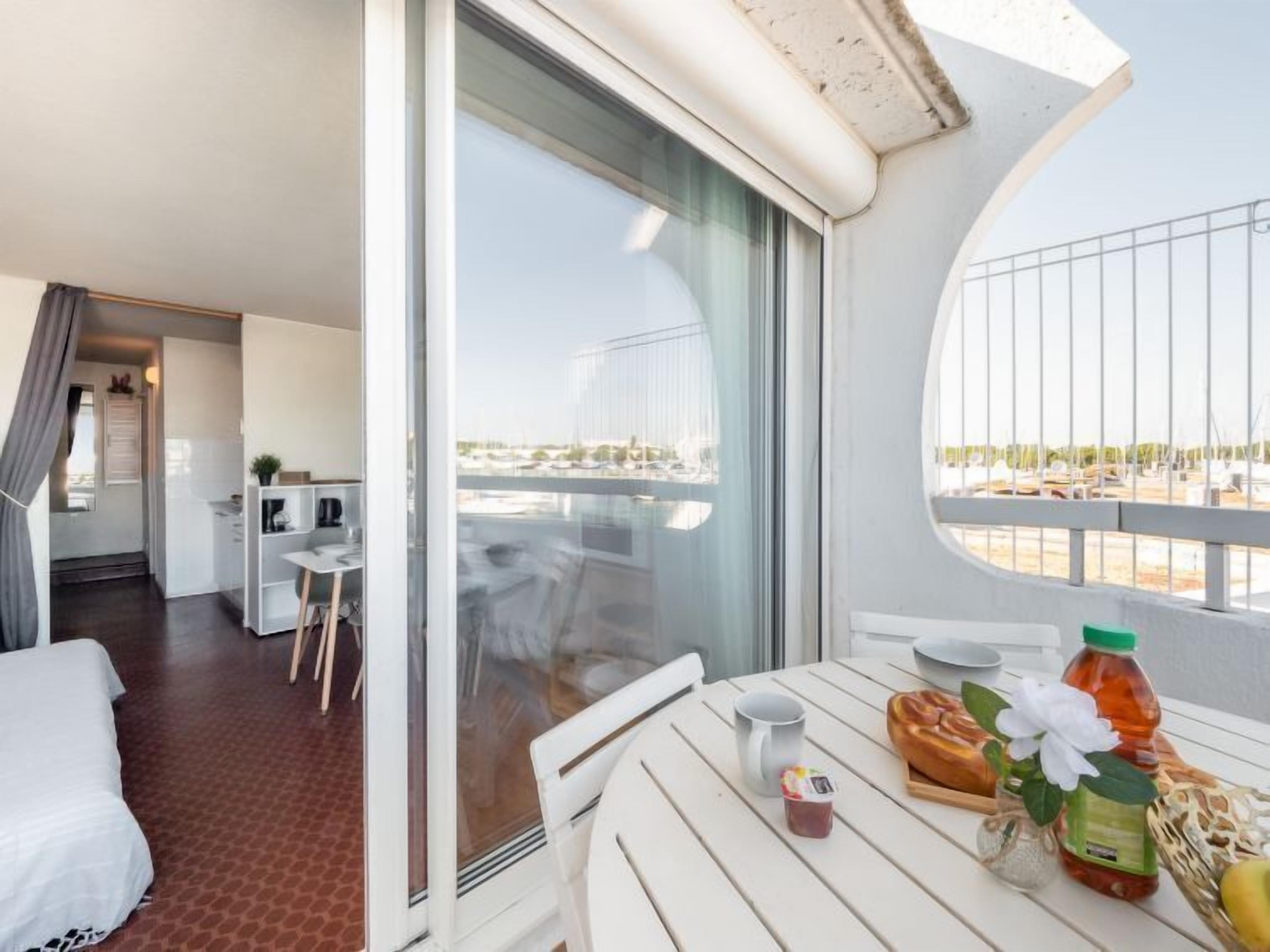 A balcony with a table set for breakfast, a chair, and a view of a marina.