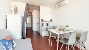 Un ambiente compatto con angolo cottura, zona pranzo e una piccola camera da letto.