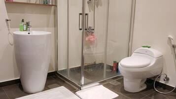 Une salle de bain avec un grand lavabo blanc, une douche à parois de verre et des toilettes.