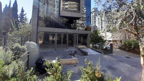 A modern building with a glass facade, outdoor seating area, and surrounding greenery. - Shade Hotel Beirut (Beirut)