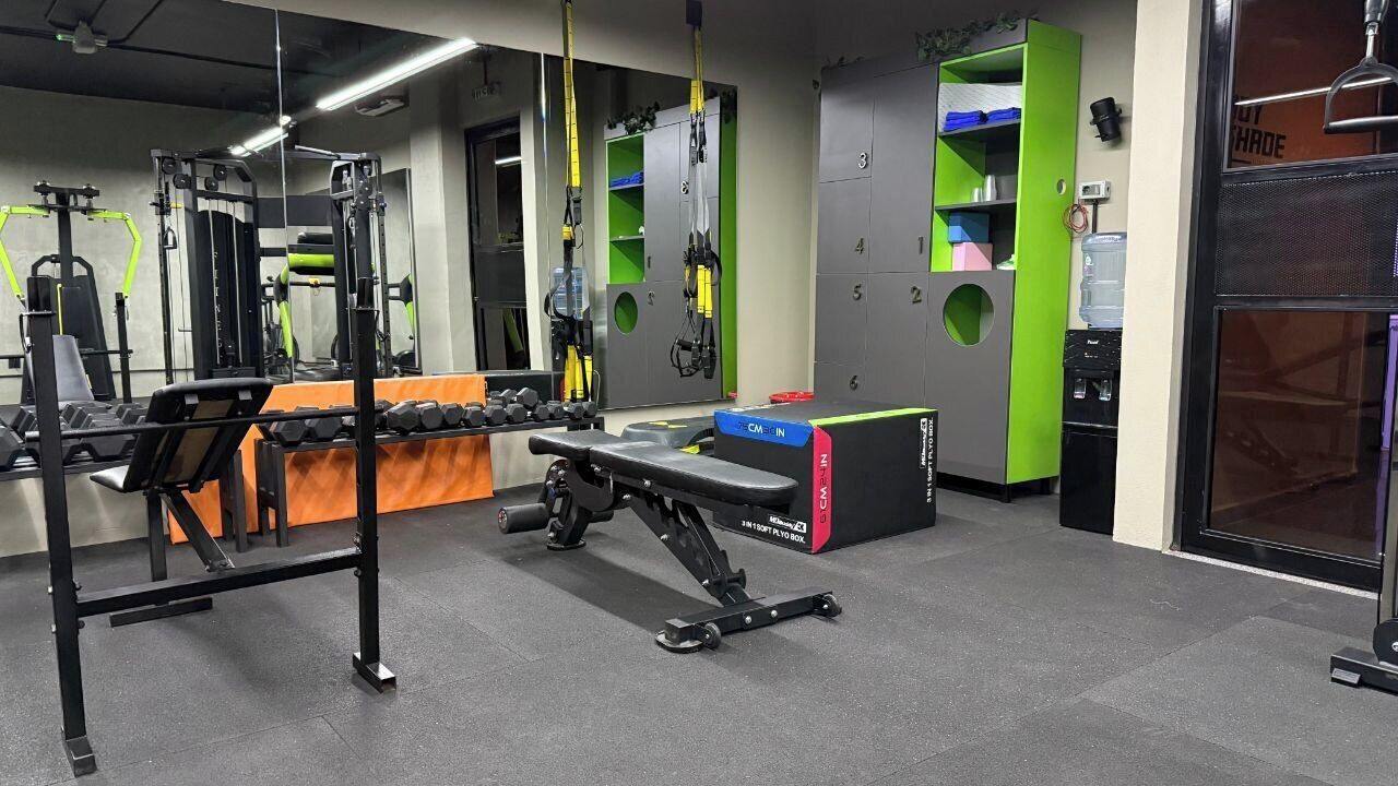 A gym with weightlifting equipment, a bench, and a mirror.