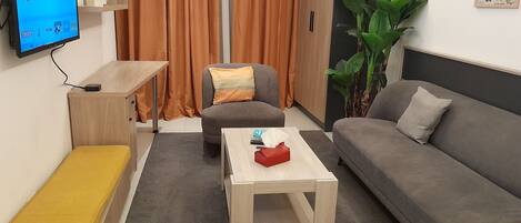 Una sala de estar moderna con un sofá, una mesa de centro, un televisor mostrando Netflix, una planta y un cuadro en la pared.