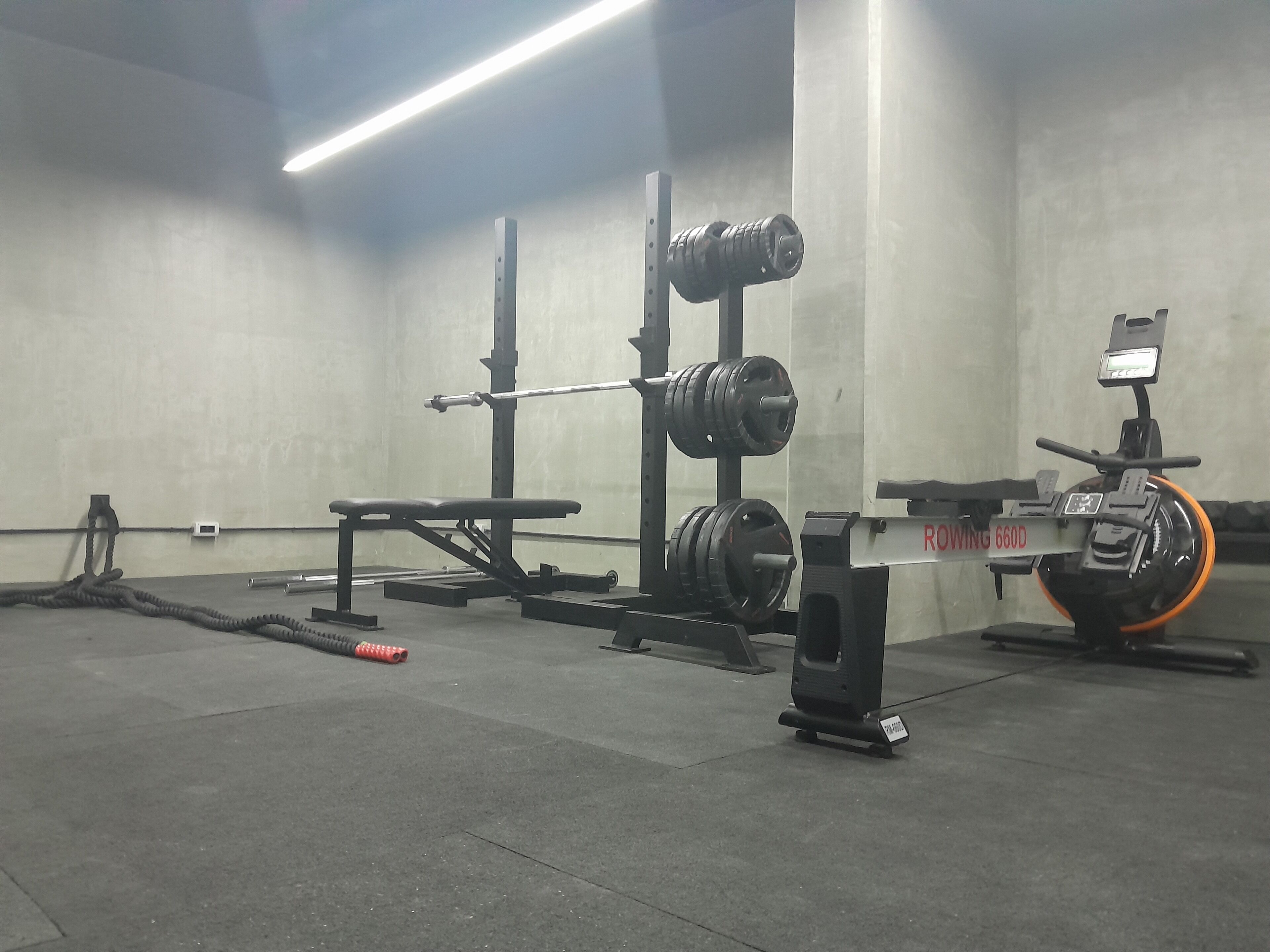 A gym with weightlifting equipment, including a bench, squat rack, and a stationary bike.