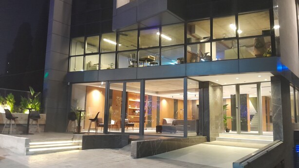 A modern hotel with a glass facade, outdoor seating area, and a staircase leading to the entrance. - Shade Hotel Beirut (Beirut)