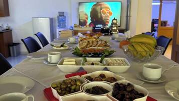 Un salón de conferencias con una larga mesa dispuesta para una reunión, equipado con un proyector y una pantalla grande.