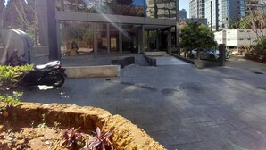 A modern building with a glass entrance, a paved courtyard, and a parked scooter. - Shade Hotel Beirut (Beirut)