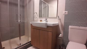 A modern bathroom with a glass-enclosed shower, a wooden vanity with a sink, and a toilet.