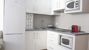 A compact kitchen with white cabinets, a built-in microwave, a toaster, and a small oven. - MONKÓ ROSARIO´S APARTMENT BEACH & SUN (Torremolinos)