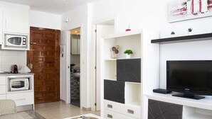 A modern living room with a flat-screen TV, a coffee machine, a microwave, and a dining area with a table and chairs. - MONKÓ ROSARIO´S APARTMENT BEACH & SUN (Torremolinos)