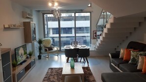 A modern living room with a dining area, a staircase, and large windows. - Amaizing Loft in Madrid Norte (Madrid)