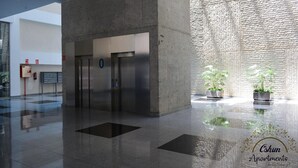 A modern lobby with a concrete reception desk, two elevators, and potted plants. - Amaizing Loft in Madrid Norte (Madrid)