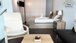 A modern hotel room with a bed, a chair, a small table with a box, a nightstand, and a sofa. - Amaizing Loft in Madrid Norte (Madrid)