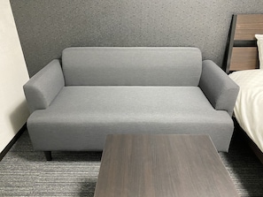 Relax in a stylish room with a sofa, side table, and comfortable bed.