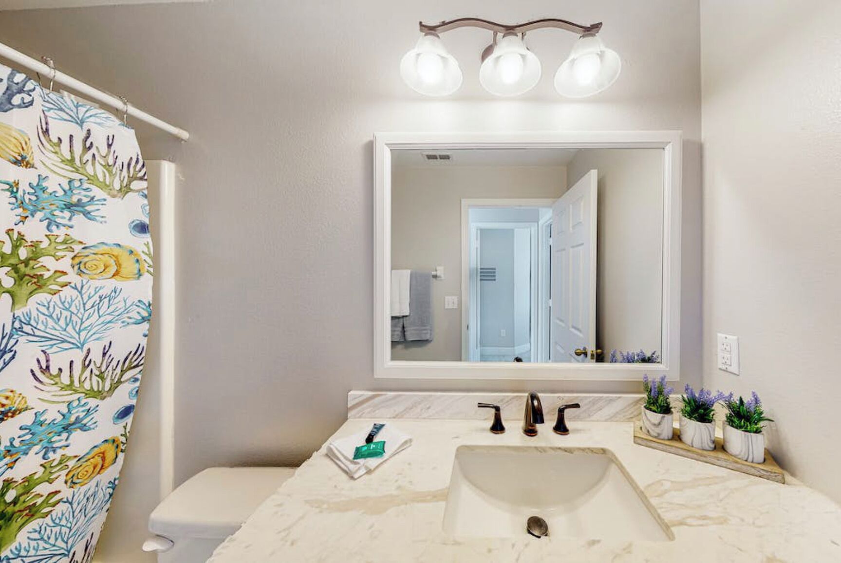 A bathroom with a white sink, a mirror, and a shower curtain with a marine design.