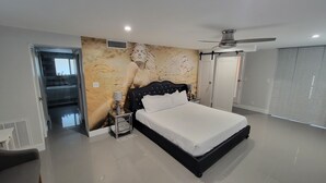 Un dormitorio moderno con una cama grande, ventilador de techo y armario.