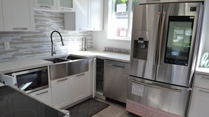 Una cocina moderna con electrodomésticos de acero inoxidable, armarios blancos y salpicadero de azulejos.