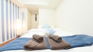 A neatly made bed with a blue blanket and two folded brown towels. - IBASHO Shibuya Dogenzaka 803 (Tokyo)