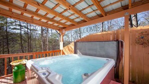 A hot tub on a wooden deck with a wooden fence and trees in the background.
