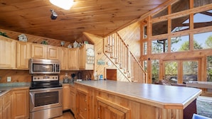 A wooden cabin kitchen with a central island, built-in oven, and microwave. - Mountain View Holy Smoky Cabin by RedAwning (Sevierville)