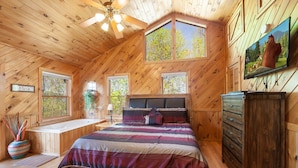 A wooden cabin bedroom with a bed, a desk, and a TV on the wall. - Mountain View Holy Smoky Cabin by RedAwning (Sevierville)