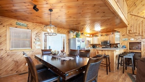 A wooden cabin interior with a dining area, kitchen, and a staircase. - Mountain View Holy Smoky Cabin by RedAwning (Sevierville)