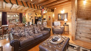 A cozy log cabin interior with a wooden dining area, a sofa, a chair, and a fireplace. - Something Extra 2 Bedroom Cabin by RedAwning (Sevierville)