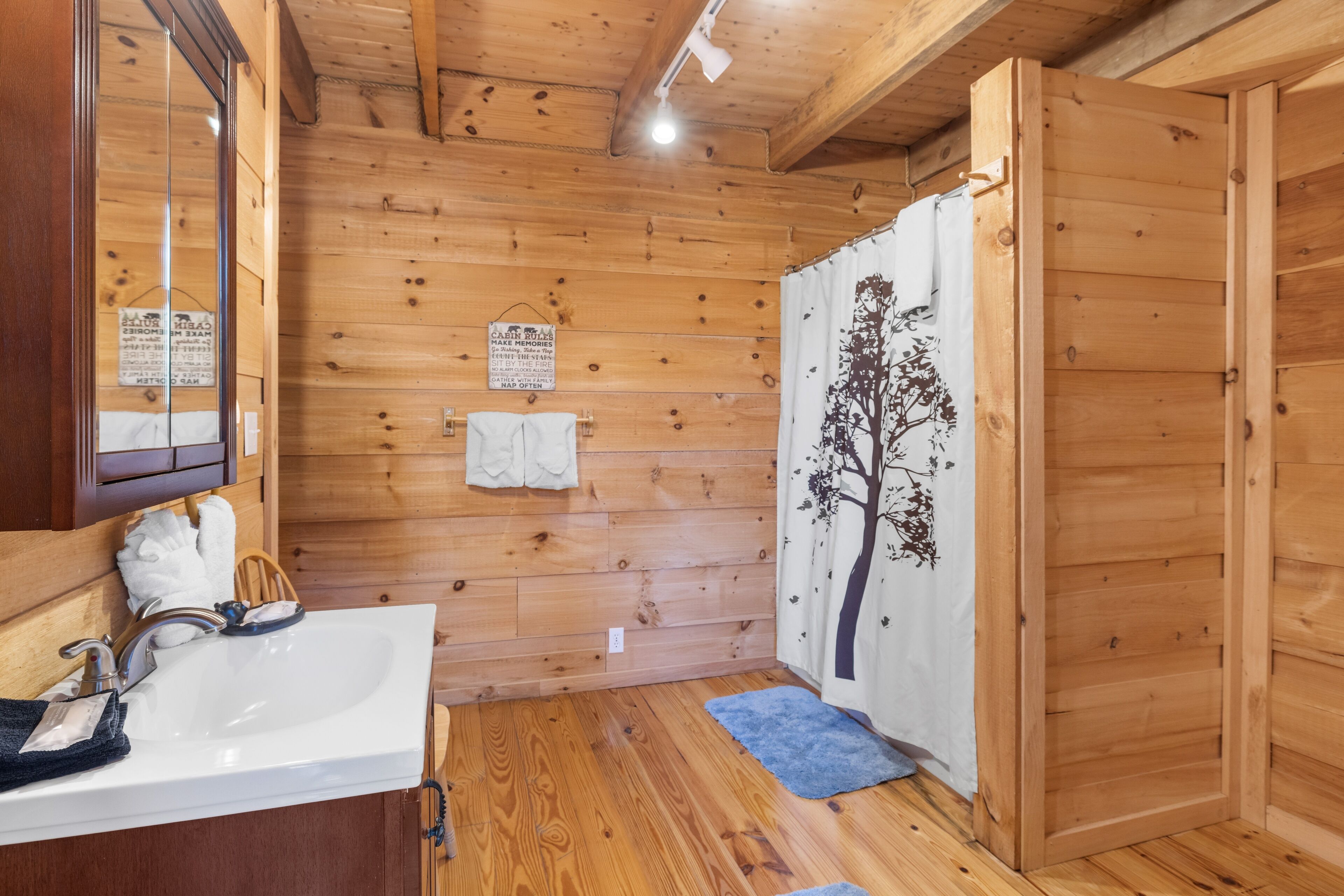 A wooden cabin bathroom with a sink, mirror, towel, and shower curtain.