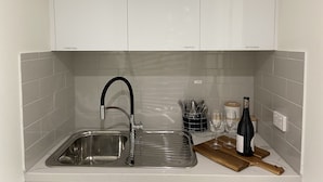 Una cucina con lavello in acciaio inossidabile, un tostapane e un portachiodi.