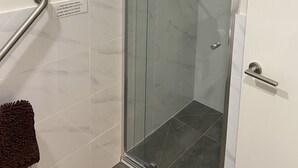 Box doccia in vetro con mancorrente e porta con maniglia.