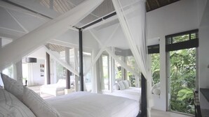 A spacious bedroom with a large bed, white bedding, and a view of lush greenery through large windows. - Ubud's Hidden Gem: Experience Luxury in Nature's Lap, Near the gates of Ubud. (Ubud)