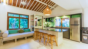 Uma cozinha moderna com teto de madeira, uma janela grande com vista para o verde, uma ilha integrada com banquetas e uma geladeira de aço inoxidável.